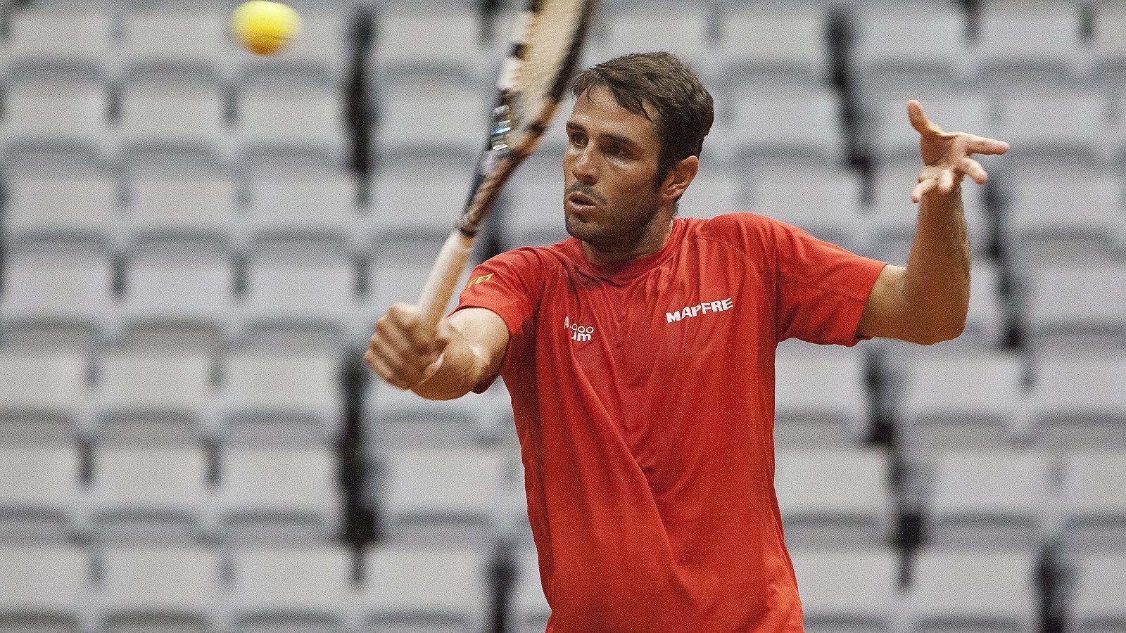 David Marrero striking a forehand in the red shirt of the Spanish Davis Cup team